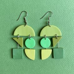 two pairs of green and yellow earrings on a green surface with silver earwires