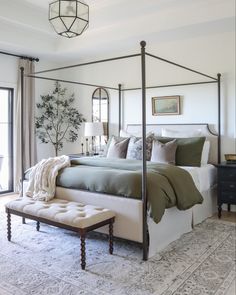 a bedroom with a canopy bed and pillows on the floor in front of a window