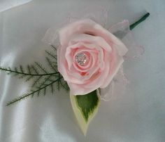 a pink rose with green leaves and a diamond in the center