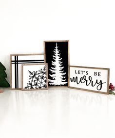 three framed christmas cards sitting on top of a white table next to a small tree