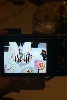 a person holding up a camera with food on it