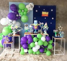 a table with balloons and other decorations on it in front of a wall that says toy story