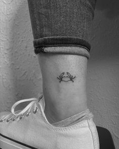 a woman's ankle with a small crab tattoo on her left side ribcage