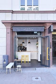 the front entrance to a restaurant with yellow chairs and tables in it's doorway