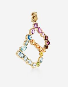 The yellow gold charm is illuminated by a veritable rainbow of natural gemstones such as topaz, garnet, amethyst, citrine, peridot and tourmaline. the shades of their colours, dominated by blue, green, purple, red, pink and yellow, evoke the warm atmospheres of Sicily. The multiple shapes of the crystals are also emphasized by the bezels, which alternate twisted thread processing and smooth surfaces. Technical specifications. Gold yellow 18 Kt. Gemstones. n.1 oval deep purple amethyst, n.1 cushion purple amethyst, n.1 drop shaped light purple amethyst, n.1 oval very light purple amethyst, n.1 round pink tourmaline, n.1 oval cabochon red violet rhodolite garnet, n.1 oval orange-red exonite garnet, n.1 oval “Madeira” quartz, n.1 round intense yellow citrine, n.1 oval yellow citrine, n.1 oval Luxury Multicolor Multi-stone Gemstones, Luxury Multicolor Gemstones With Accents, Very Light Purple, Rainbow Alphabet, Red Violet, Yellow Citrine, Rhodolite Garnet, Gold Fashion, Oval Cabochon