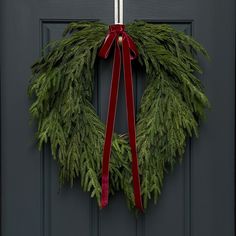 a christmas wreath hanging on a door with a red ribbon around it's edge