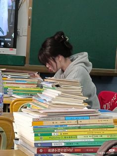 a woman sitting at a desk with stacks of books