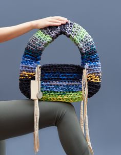 a woman holding a multicolored crocheted purse