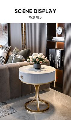 a table with flowers on it in front of a couch and bookshelf that says scene display