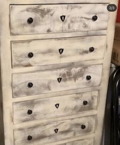 an old dresser is painted white with black knobs