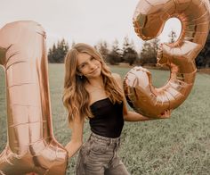 a woman is holding two large gold balloons