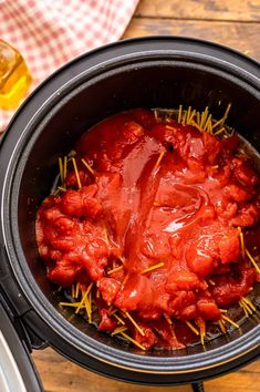 a slow cooker filled with meat and sauce