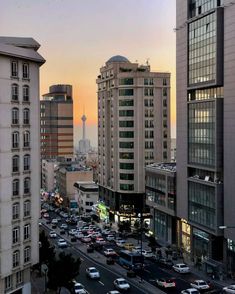 a city street filled with lots of traffic next to tall buildings and tall skyscrapers