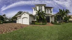 a large white house with palm trees in the front yard and landscaping on both sides