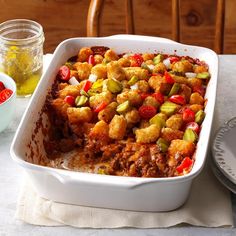 a casserole dish with meat and vegetables in it on a white table cloth