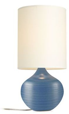 a blue table lamp with a white shade on the base and a light in front of it