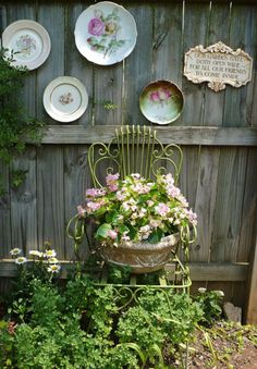 a chair with flowers in it sitting next to plates on a fenced in area