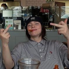 two people sitting at a table with food in front of them and one person making the peace sign