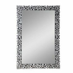 a mirror that is sitting on top of a white surface with black and silver decorations