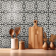 an assortment of kitchen utensils and wooden spoons sit on a table in front of a patterned wall