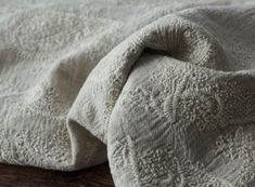 an unmade bedspread on top of a wooden table with a white comforter