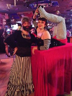 a man and woman dressed up in costume posing for a photo with a table cloth draped over them