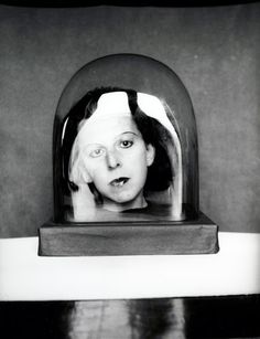 a black and white photo of a woman's face through a glass dome on a table