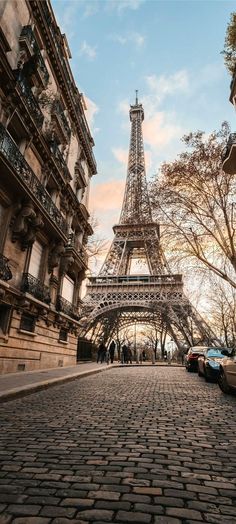 the eiffel tower in paris, france is seen from an old cobblestone street