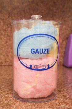 a cup filled with pink, blue and yellow colored cotton sitting on top of a counter