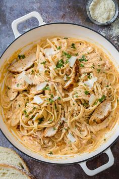 pasta with chicken and parmesan cheese in a skillet next to garlic bread