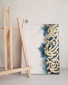 an easel next to a painting with gold lettering on it