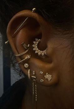 a woman's ear with multiple piercings and dangling earrings on top of it