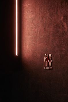 a red wall with two people on it and the word toilet written in gold foil