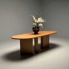 a vase with flowers sitting on top of a wooden table in the middle of a room