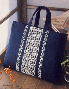 a blue and white bag sitting on top of a wooden floor next to some flowers