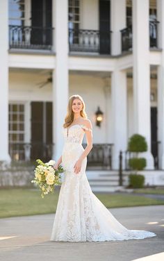 a woman standing in front of a large white building wearing a wedding dress and holding a bouquet