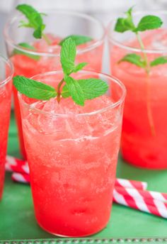 four glasses filled with watermelon and mint sprigs on a green tray