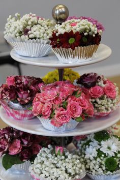 three tiered trays filled with flowers and cupcakes