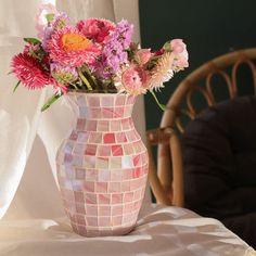 a vase filled with lots of flowers sitting on top of a table next to a chair