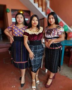 three women standing next to each other in front of a staircase