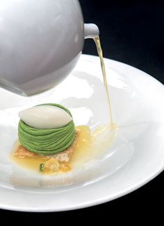 a white plate topped with a pastry covered in icing next to a tea pot