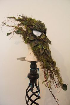 a head made out of branches and moss on a stand with a light bulb in the middle