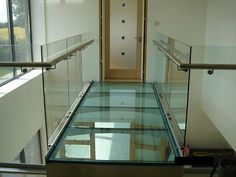 an empty glass floor in the middle of a hallway with stairs leading up to it