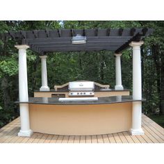 an outdoor bbq with grill and counter top on a deck in front of trees