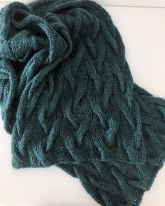 a green knitted scarf sitting on top of a white table