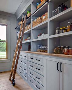 a ladder is in the middle of a kitchen with white cabinets and drawers on it