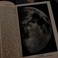 an open book with the moon on it's cover and some writing in front of it