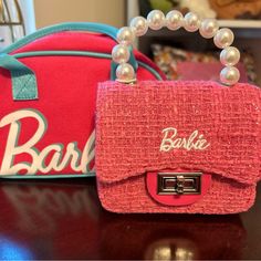 two purses sitting on top of a table next to each other with pearls around them