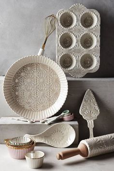 an assortment of kitchen utensils and baking supplies on display in front of a gray wall