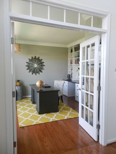 a room with a desk, chair and bookshelf on the other side of the door